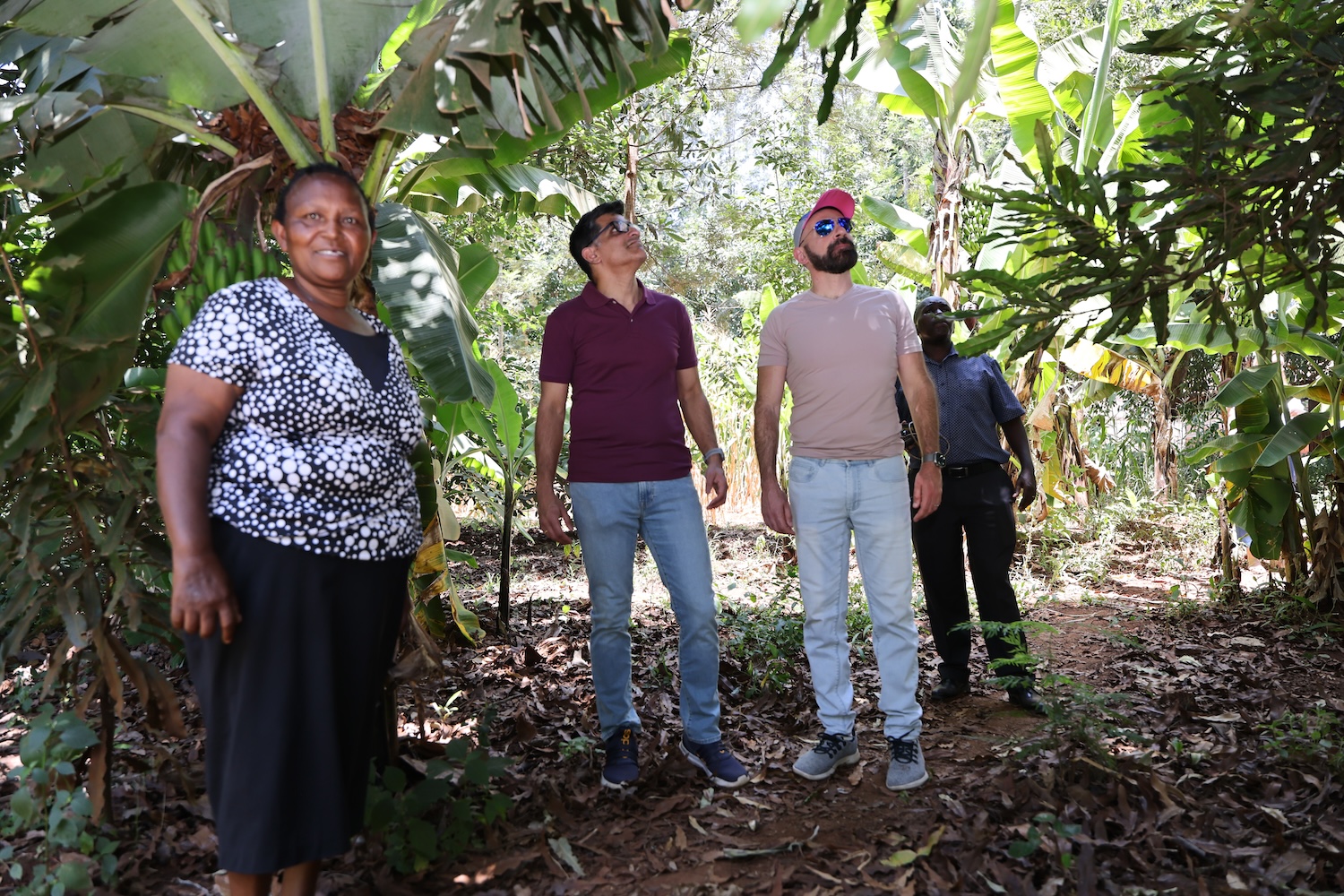 Lucy, a farmer from Kenya, shows Vishal and Andre her crops